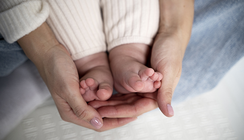 Mãos de mulher adulta segurando pé de bebê