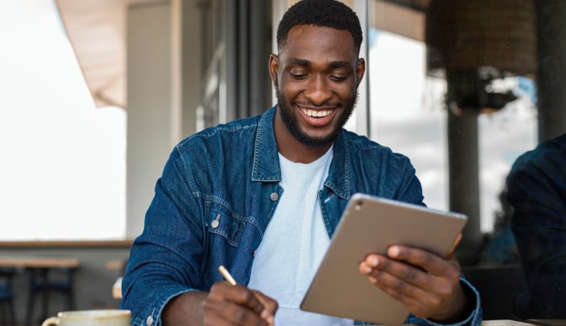 Homem sorridente trabalhando com tablet na mão